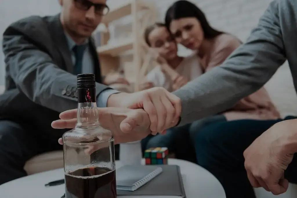 A family together while one person reaches out to stop another drinking