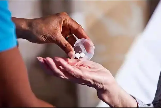 Tablets being poured from a cup into a person’s open palm