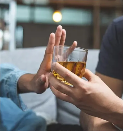 A hand declining an offered glass of whisky